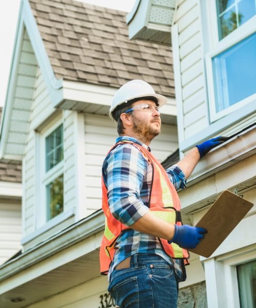 A,Man,With,Hard,Hat,Standing,On,Steps,Inspecting,House